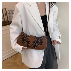 Détail du sac léopard avec rabat en forme d'éclair porté sur une veste de blazer blanche
