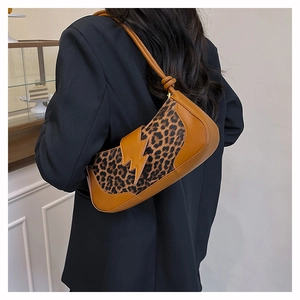 Détail du sac d'épaule léopard avec patch éclair en cuir porté sur un costume noir chic