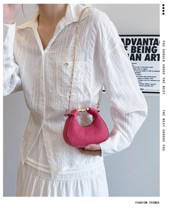 Détail du sac croissant fuchsia froncé avec chaîne dorée et poignée en métal sur modèle