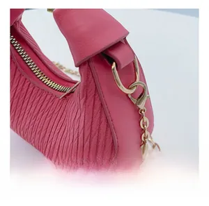 Gros plan du sac à main plissé rose vif avec chaîne en métal doré et crochets