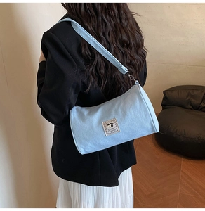 Close-up of light blue canvas shoulder bag with cartoon patch and adjustable strap