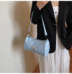 Detail view of light blue canvas pillow bag with cute cartoon patch and black metal hooks