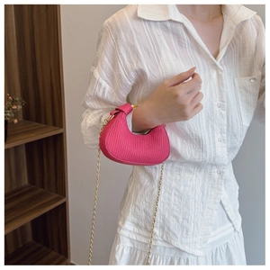 Détail du sac demi-lune rose avec texture plissée et bandoulière en chaîne dorée