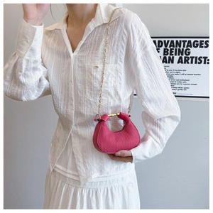 Mannequin portant un sac demi-lune plissé rose avec bandoulière chaîne dorée en studio