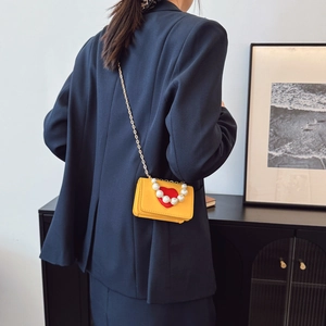 Mini sac bandoulière jaune avec cœur rouge et anse perle sur blazer bleu