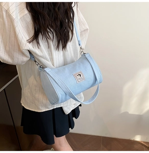 Detail shot of the light blue canvas pillow bag featuring a cute dog woven patch and strap