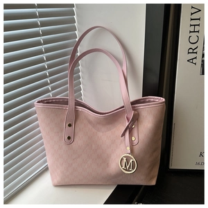 Detail of light pink tote bag with textured finish and gold M letter pendant charm