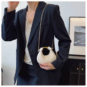 Détail du sac demi-lune plissé beige avec poignée dorée et bandoulière en chaîne