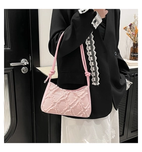 Vista laterale di una borsa baguette rosa testurizzata con frange e tracolla con nodo trendy