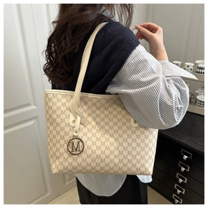 Detail view of large capacity tote bag with M-letter print and round metal pendant