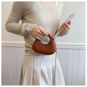 Détail du sac demi-lune plissé caramel assorti à une tenue de tons neutres