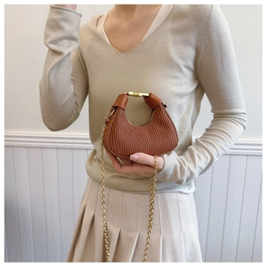 Détail d'un sac hobo croissant marron avec texture plissée et poignée dorée