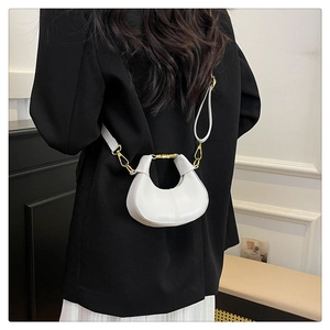 Detail of white half-moon mini crossbody bag with gold metal ring and leather strap