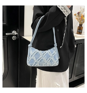 Dettaglio borsa a tracolla in denim celeste con trapuntatura a rombi e tracolla annodata