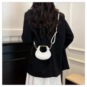 Vue détaillée d'un sac bandoulière blanc en forme de lune avec des boucles en métal doré