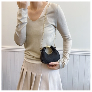 Détail du mini sac hobo noir avec texture plissée et chaîne dorée sur modèle