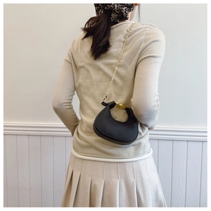Détail du sac demi-lune noir en cuir texturé avec chaîne dorée sur mannequin