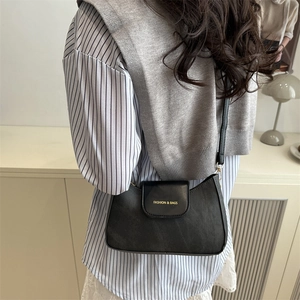 Borsa sottobraccio classica in pelle PU nera con scritte dorate su un modello alla moda
