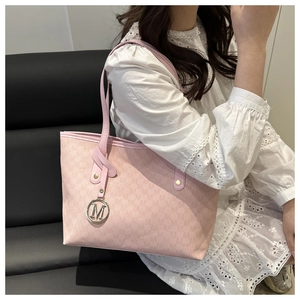 Detail of pink tote bag with monogram pattern and metallic M-shaped brand pendant