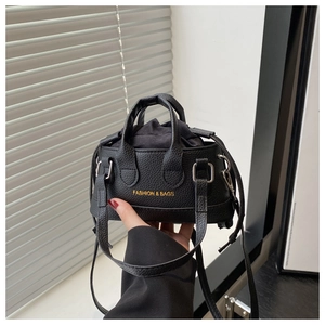Close-up of black lychee leather mini drawstring bag with gold lettering detail