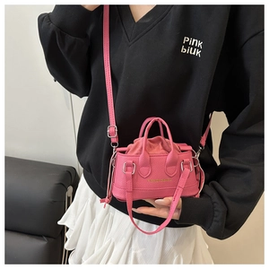 Close-up of mini pink drawstring handbag with lychee texture leather and gold buckle