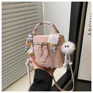 Detail of pink leather box bag with silk scarf handle and plush monster charm decoration