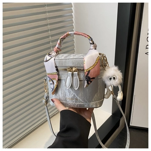 Detail of marble textured bucket bag with decorative silk scarf and furry charm pendant