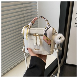 Detail of white box bag with lychee leather, silk scarf handle and fluffy pom charm