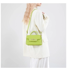 Side view of lime green PU leather handbag with metal lock buckle on white blazer