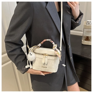 Detail of white box handbag with silk scarf handle and plush ball charm on a model