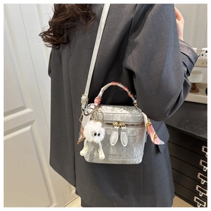 Detail of silver textured box bag with silk scarf and plush charm worn by model