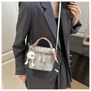 Detail of silver textured bucket bag with fashion print scarf and plush charm accessory