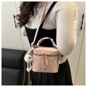Pink crossbody bucket bag with silk scarf handle and plush pendant in model back view