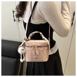 Pink bucket bag with silk scarf handle and fluffy keychain charm on model