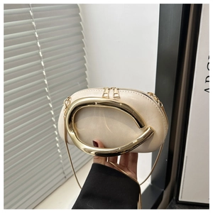 Detailed view of cream PU leather handbag featuring a large gold horseshoe metal handle