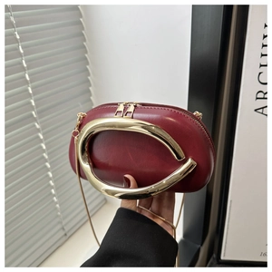 Macro view of burgundy leather mini box bag with gold horseshoe handle and chain strap