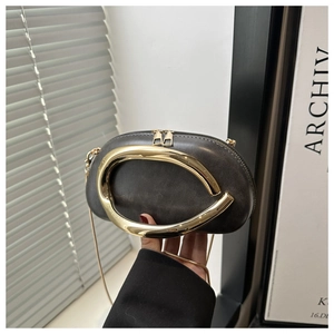 Detailed view of dark grey leather handbag with gold metal handle and chain strap