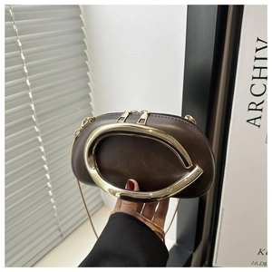 Detail of burgundy metal box clutch with gold oval handle and chain strap