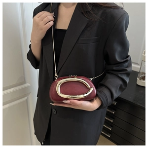 Close-up of vintage burgundy square handbag with golden C-handle and chain strap