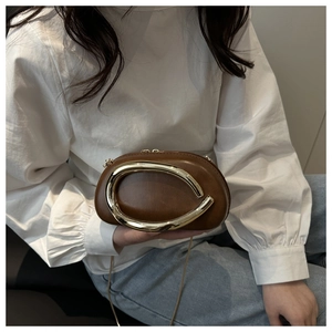 Close-up of brown leather evening bag with prominent gold ring buckle and chain strap