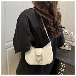 Detailansicht einer weißen Halbmond-Tasche mit goldener U-Schnalle an einem Modell