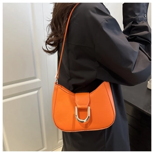 Close-up of vibrant orange hobo bag with large silver U-shaped metal buckle and leather texture
