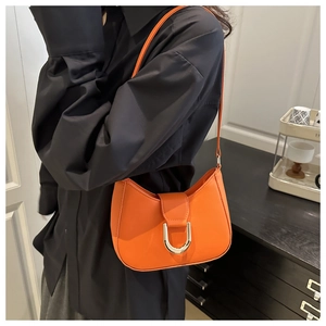 Details der leuchtend orangefarbenen Halbmond-Tasche mit polierter silberner Hufeisenschnalle