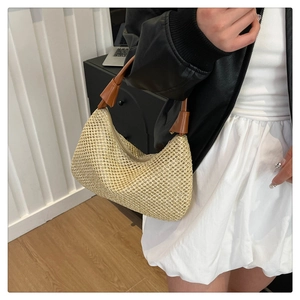 Detail der handgewebten Hobo-Bag mit beiger Baststruktur und braunem Kunstledergriff