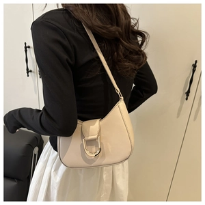 Nahaufnahme einer cremefarbenen Halbmond-Tasche mit eleganter goldener Hufeisenschnalle