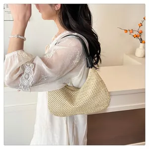 Detail der gewebten Stroh-Hobo-Tasche mit schwarzem Leder-Schultergurt am Model