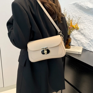 Sac à bandoulière chic en cuir beige avec fermoir en T doré sur un modèle