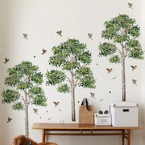 Detail of birch tree wall stickers with green leaves and flying birds in a cozy room