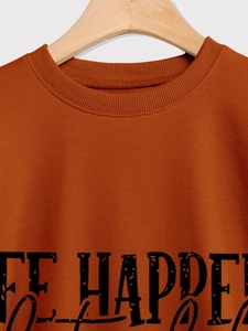 Detail of ribbed neckline and black lettering on orange long sleeve sweatshirt