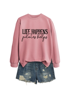 Detailed flat lay of pink Life Happens Pilates Helps sweatshirt and ripped denim shorts